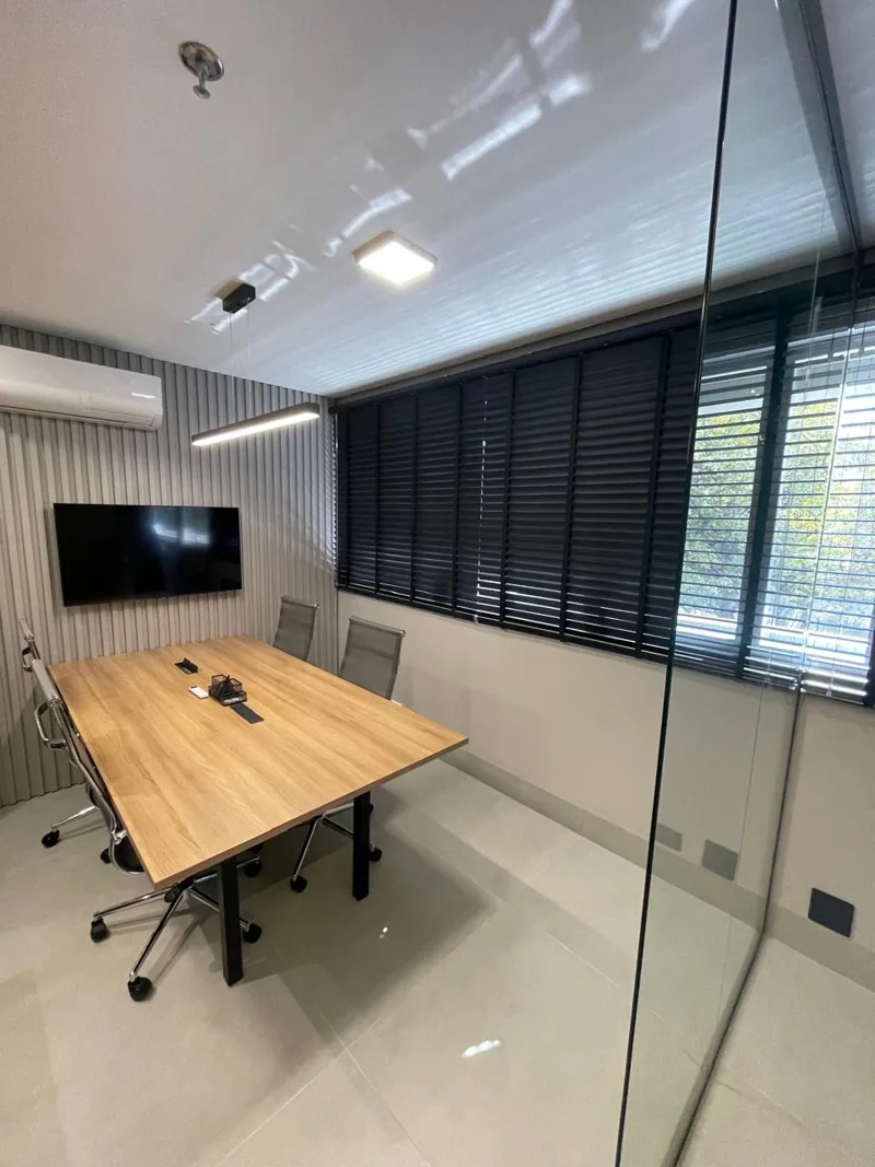 Sala de reuniões com mesa de madeira e televisão desligada
