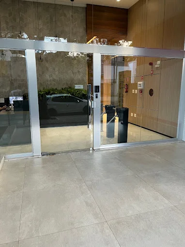 Porta de vidro da portaria do Centro Empresarial Maximum vista de fora, com catracas atrás do vidro